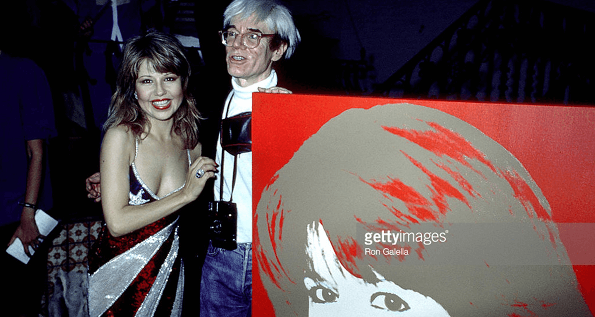 A man and woman posing with an andy warhol painting.